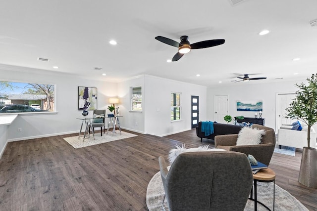 living area featuring wood finished floors, visible vents, crown molding, and ceiling fan