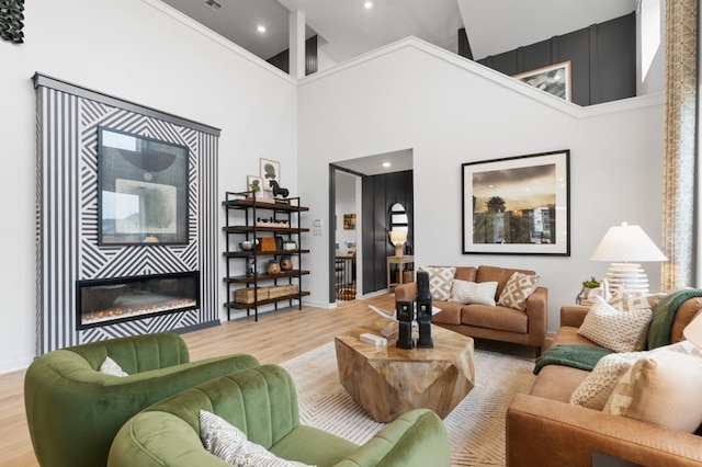 2705 Sage Ranch Dr Unit 32, Leander, TX 78641 - living room featuring a high ceiling, wood finished floors, a glass covered fireplace, recessed lighting, and baseboards