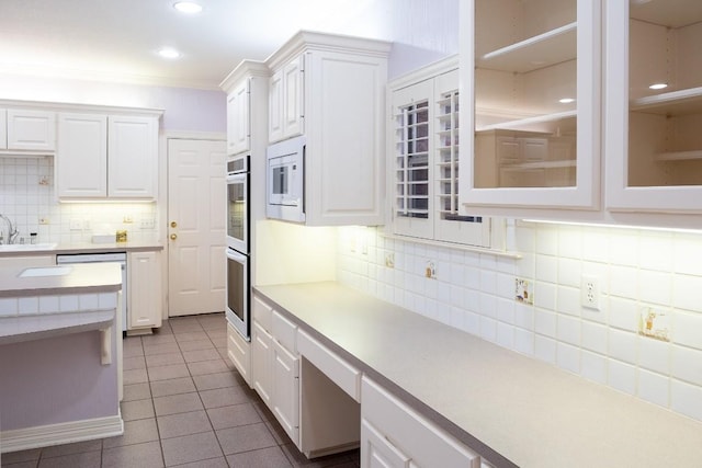 kitchen with white cabinetry, light countertops, white microwave, and dark tile patterned floors