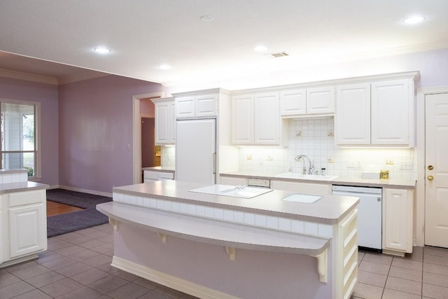 kitchen featuring light countertops, a sink, backsplash, refrigerator, and dishwasher