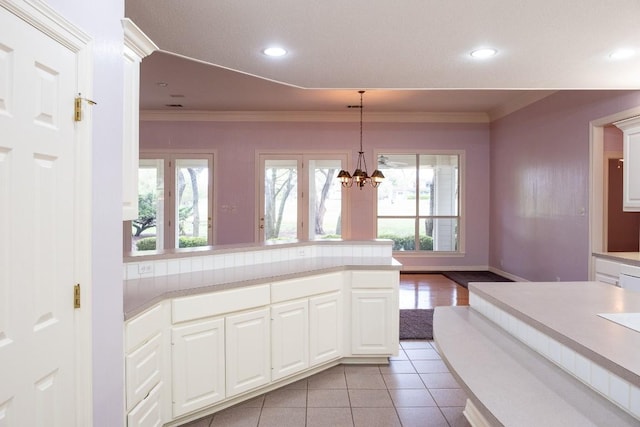 kitchen featuring light countertops, light tile patterned floors, white cabinetry, and crown molding