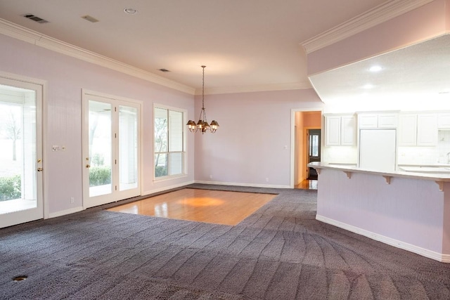 unfurnished dining area with baseboards, ornamental molding, visible vents, and dark colored carpet