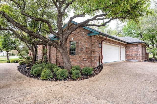 view of property exterior with an attached garage, brick siding, and concrete driveway