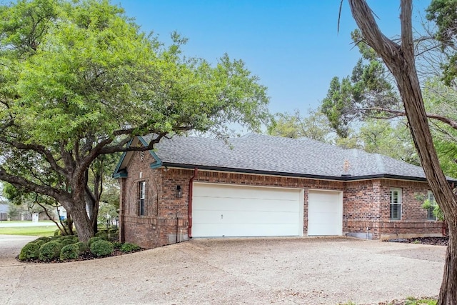 view of home's exterior with roof with shingles, an attached garage, brick siding, and concrete driveway