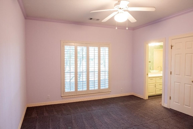 spare room featuring dark carpet, crown molding, baseboards, visible vents, and ceiling fan