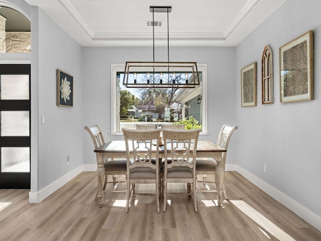 dining space with visible vents, baseboards, a notable chandelier, light wood-style floors, and a tray ceiling
