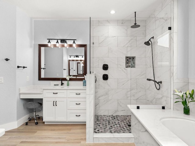 bathroom featuring a bath, tiled shower, vanity, wood finished floors, and baseboards