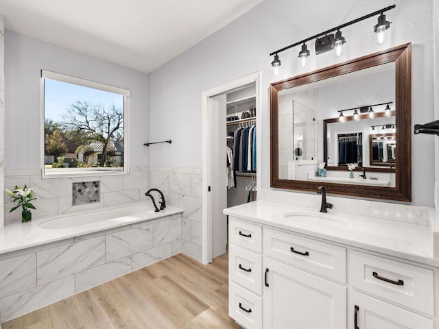 103 Waters Edge, Horseshoe Bay, TX 78657 - full bath with vanity, a garden tub, a spacious closet, and wood finished floors