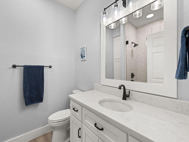 103 Waters Edge, Horseshoe Bay, TX 78657 - full bathroom featuring vanity, a tile shower, toilet, wood finished floors, and baseboards