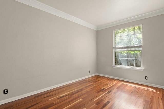 unfurnished room featuring hardwood / wood-style floors, ornamental molding, and baseboards