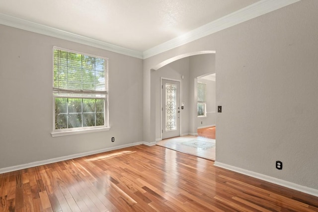 foyer with baseboards, arched walkways, wood finished floors, and crown molding
