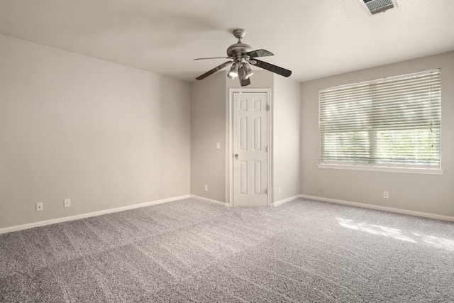 carpeted spare room with baseboards, visible vents, and a ceiling fan