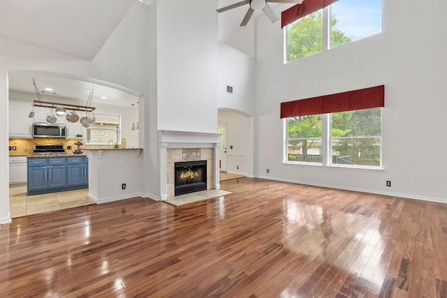 1103 Vanderbilt Cir, Pflugerville, TX 78660 - unfurnished living room with a ceiling fan, light wood-style floors, healthy amount of natural light, and a high ceiling