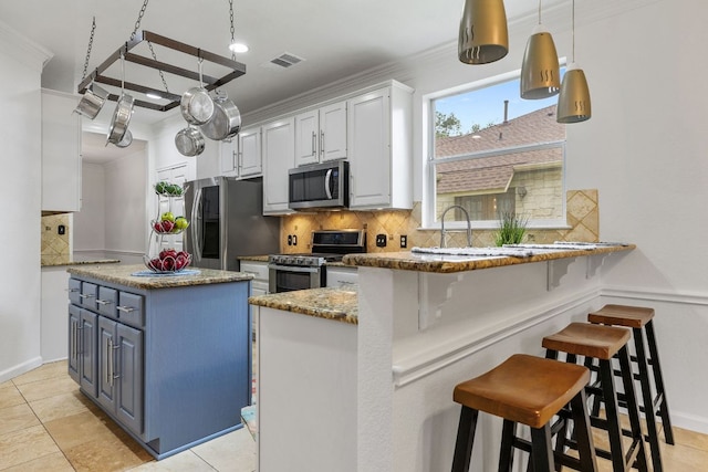 1103 Vanderbilt Cir, Pflugerville, TX 78660 - kitchen with appliances with stainless steel finishes, ornamental molding, decorative backsplash, white cabinetry, and a kitchen island