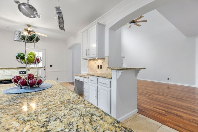 1103 Vanderbilt Cir, Pflugerville, TX 78660 - kitchen with a ceiling fan, arched walkways, tasteful backsplash, light stone countertops, and light tile patterned floors