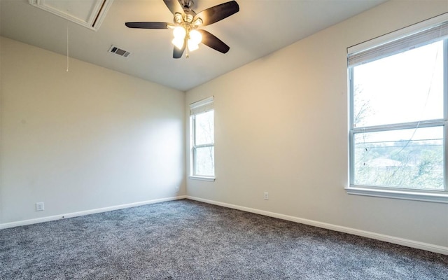 carpeted spare room with baseboards, a ceiling fan, visible vents, and attic access