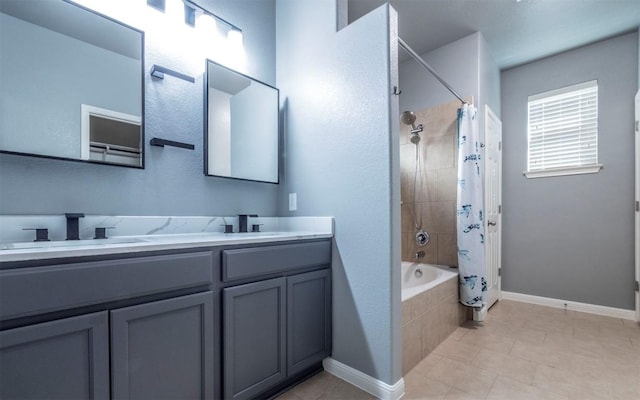 full bath featuring baseboards, double vanity, a sink, and tiled shower / bath combo