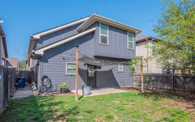 rear view of house featuring a fenced backyard, a lawn, a patio area, and board and batten siding