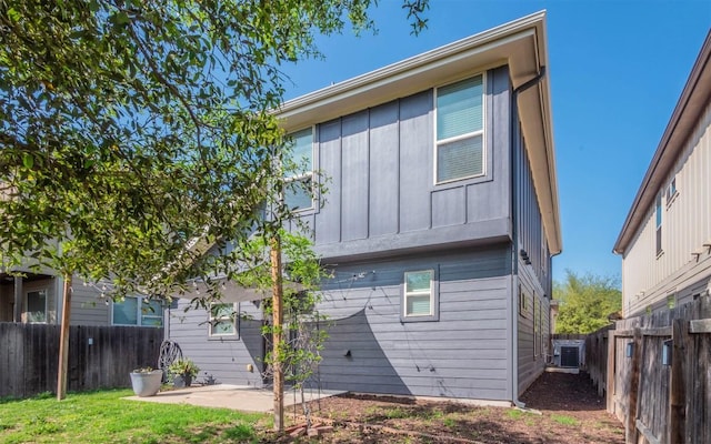 back of house featuring central AC unit, a fenced backyard, board and batten siding, and a patio area