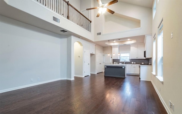 7337 Menchaca Rd Unit 31, Austin, TX 78745 - unfurnished living room with ceiling fan, dark wood-type flooring, arched walkways, a towering ceiling, and a sink