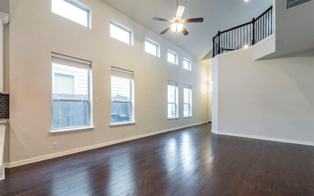 unfurnished living room with baseboards, a high ceiling, dark wood-style floors, visible vents, and a ceiling fan