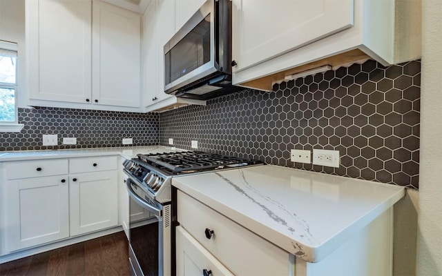 kitchen with dark wood finished floors, white cabinetry, decorative backsplash, and appliances with stainless steel finishes