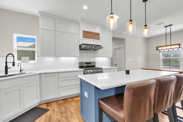 414 Wesley Ridge Dr, Spicewood, TX 78669 - kitchen featuring stainless steel gas range oven, light countertops, a kitchen breakfast bar, white cabinetry, and recessed lighting
