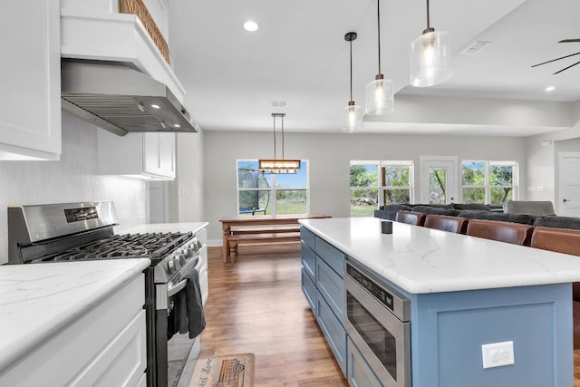 414 Wesley Ridge Dr, Spicewood, TX 78669 - kitchen featuring stainless steel appliances, ventilation hood, blue cabinets, white cabinetry, and recessed lighting