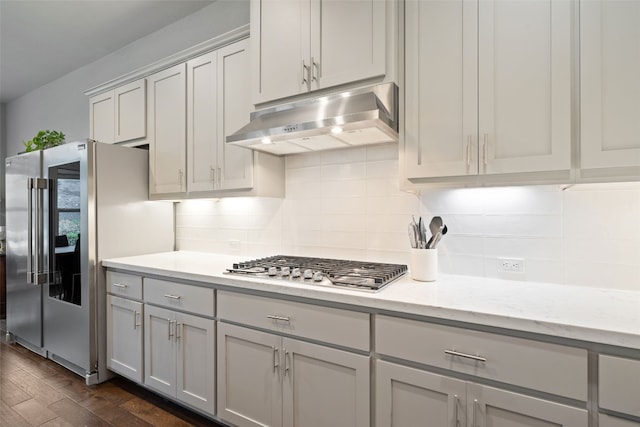 308 Highland Village Cv, Austin, TX 78738 - kitchen featuring range hood, appliances with stainless steel finishes, dark wood-style flooring, tasteful backsplash, and light stone counters