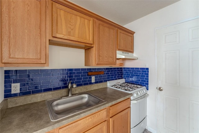 kitchen with white gas range oven, a sink, tasteful backsplash, and under cabinet range hood