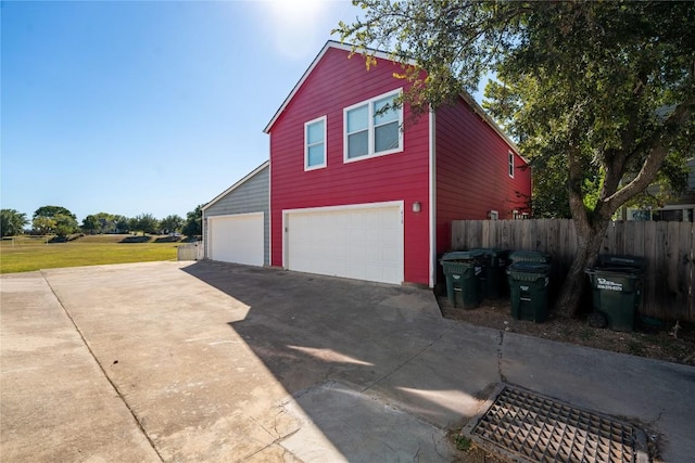detached garage featuring driveway and fence