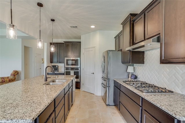 334 Sapling Dr, Driftwood, TX 78619 - kitchen featuring under cabinet range hood, appliances with stainless steel finishes, dark brown cabinets, tasteful backsplash, and light stone counters