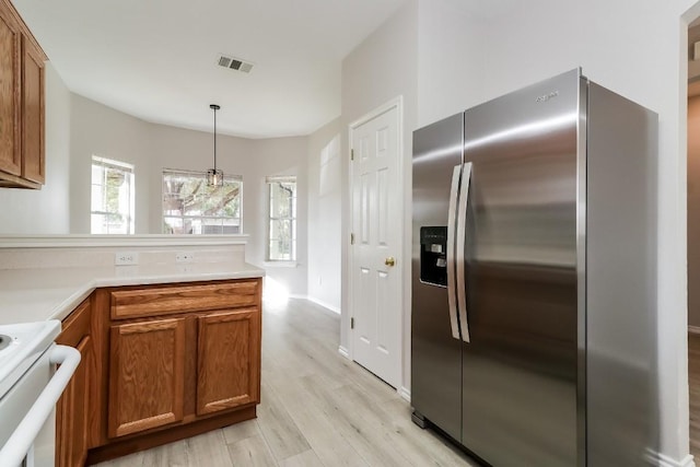 kitchen featuring stainless steel refrigerator with ice dispenser, light wood-style floors, pendant lighting, visible vents, and brown cabinetry