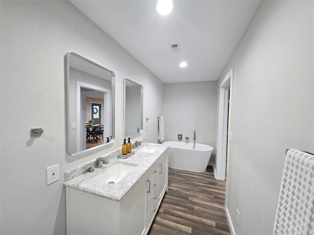 507 W 1st St, Flatonia, TX 78941 - full bathroom with wood finished floors, double vanity, a soaking tub, and recessed lighting
