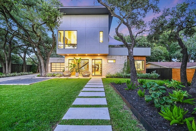 403 Ridgewood, Austin, TX 78746 - back of house at dusk with a yard, fence, stucco siding, and stone siding