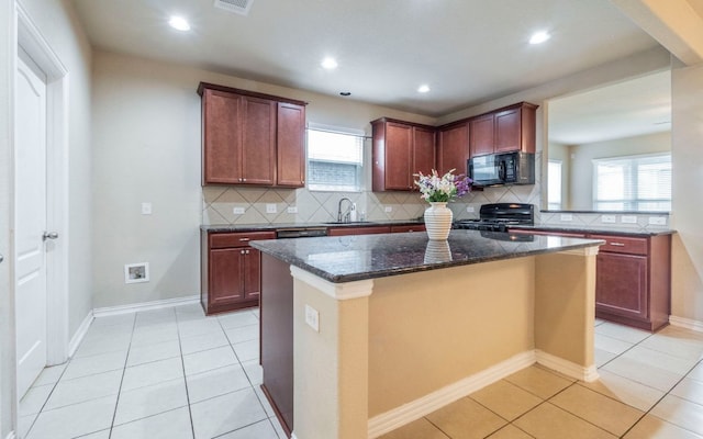 8021 Arezzo Dr, Round Rock, TX 78665 - kitchen featuring stove, black microwave, a sink, a kitchen island, and decorative backsplash