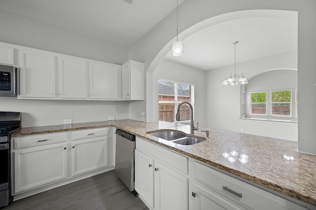 720 Northcreek Blvd, Leander, TX 78641 - kitchen featuring stainless steel appliances, white cabinets, light stone counters, arched walkways, and dark wood-style flooring