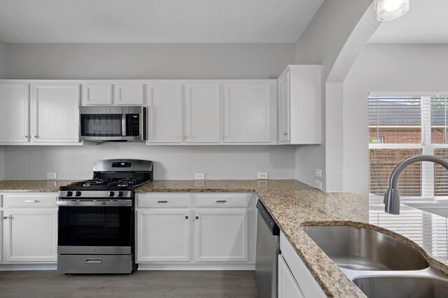720 Northcreek Blvd, Leander, TX 78641 - kitchen featuring appliances with stainless steel finishes, white cabinets, light stone countertops, and wood finished floors