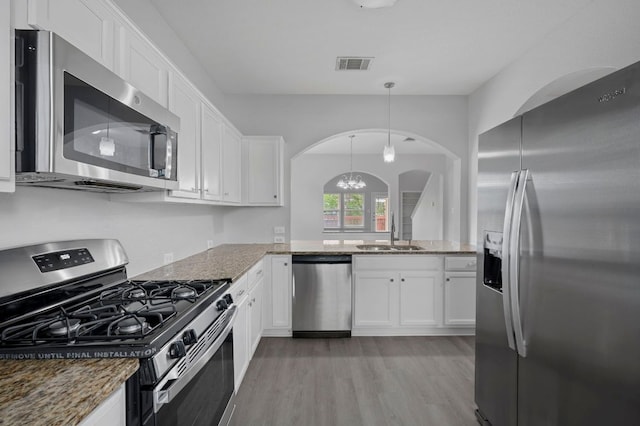 720 Northcreek Blvd, Leander, TX 78641 - kitchen featuring appliances with stainless steel finishes, arched walkways, light wood-type flooring, and white cabinets