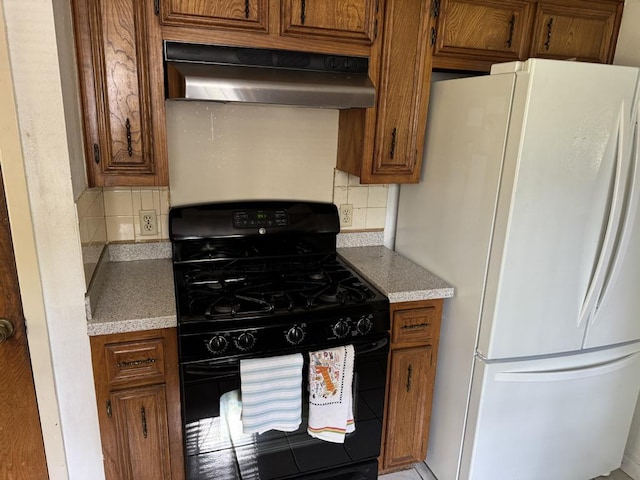 11202 Balcones Woods Cv, Austin, TX 78759 - kitchen with freestanding refrigerator, black gas range, under cabinet range hood, backsplash, and brown cabinets