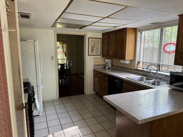 11202 Balcones Woods Cv, Austin, TX 78759 - kitchen with black appliances, light tile patterned floors, light countertops, a peninsula, and a textured ceiling
