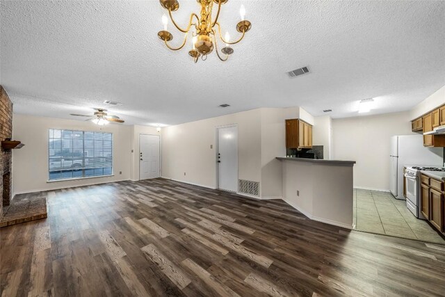8802 Peppergrass Cv, Austin, TX 78745 - unfurnished living room featuring a textured ceiling, dark wood finished floors, a chandelier, a ceiling fan, and a fireplace