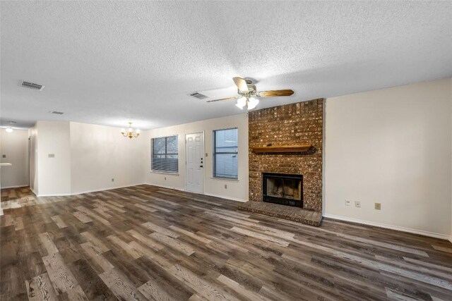 8802 Peppergrass Cv, Austin, TX 78745 - unfurnished living room featuring dark wood finished floors, a textured ceiling, a chandelier, a fireplace, and a ceiling fan