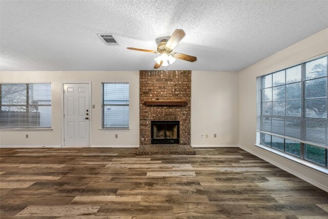 8802 Peppergrass Cv, Austin, TX 78745 - unfurnished living room featuring a textured ceiling, wood finished floors, a ceiling fan, and a fireplace