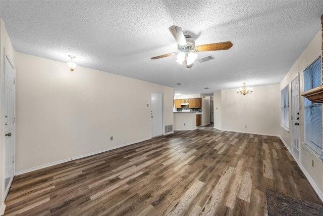 8802 Peppergrass Cv, Austin, TX 78745 - unfurnished living room with ceiling fan, dark wood-type flooring, a chandelier, and a textured ceiling
