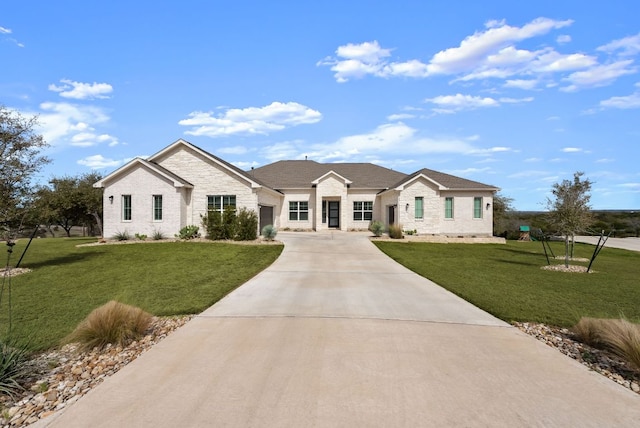 single story home featuring concrete driveway, brick siding, and a front lawn