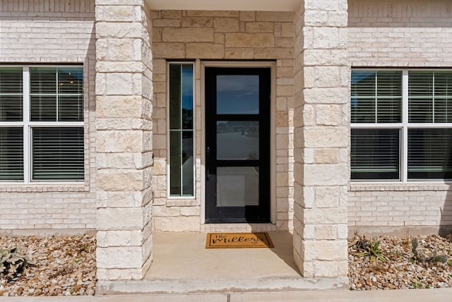 doorway to property featuring brick siding and stone siding