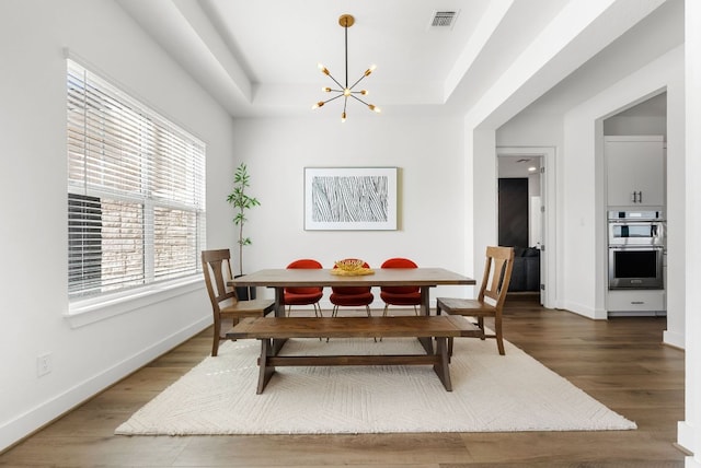 dining room with a tray ceiling, an inviting chandelier, baseboards, and visible vents