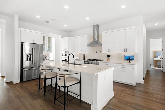 kitchen featuring a sink, dark wood-style flooring, appliances with stainless steel finishes, and wall chimney range hood