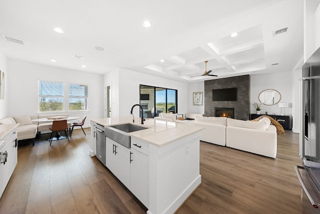 kitchen with a sink, a fireplace, a ceiling fan, open floor plan, and visible vents